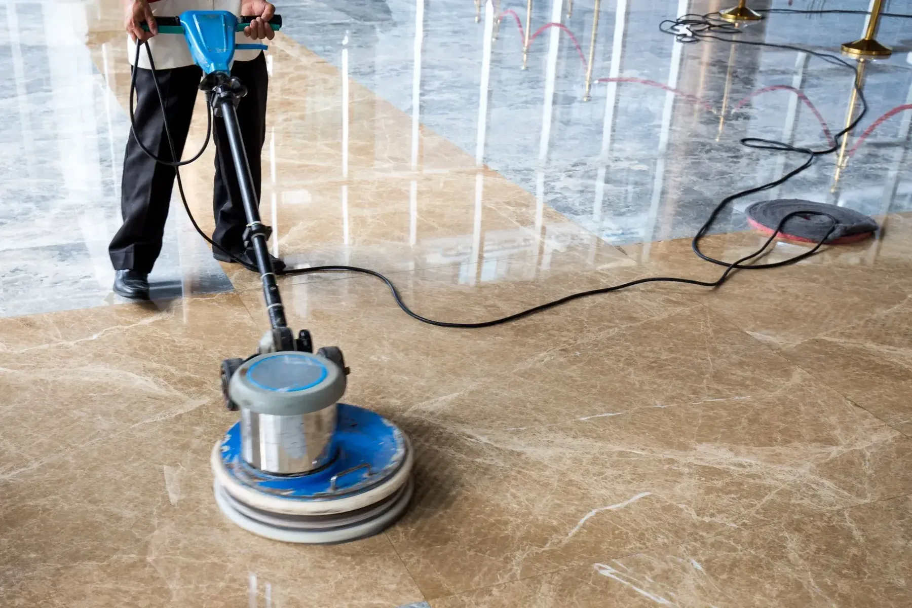 Worker running a polishing machine over a glossy stone-look floor