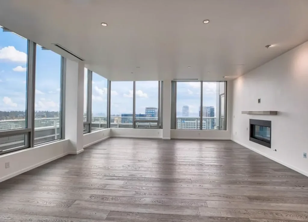 Empty condo living room with a grey wood-look plank floor and floor-to-ceiling windows