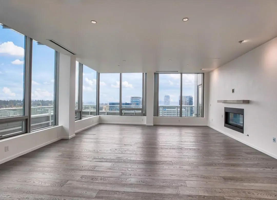 Empty condo living room with a grey wood-look plank floor and floor-to-ceiling windows