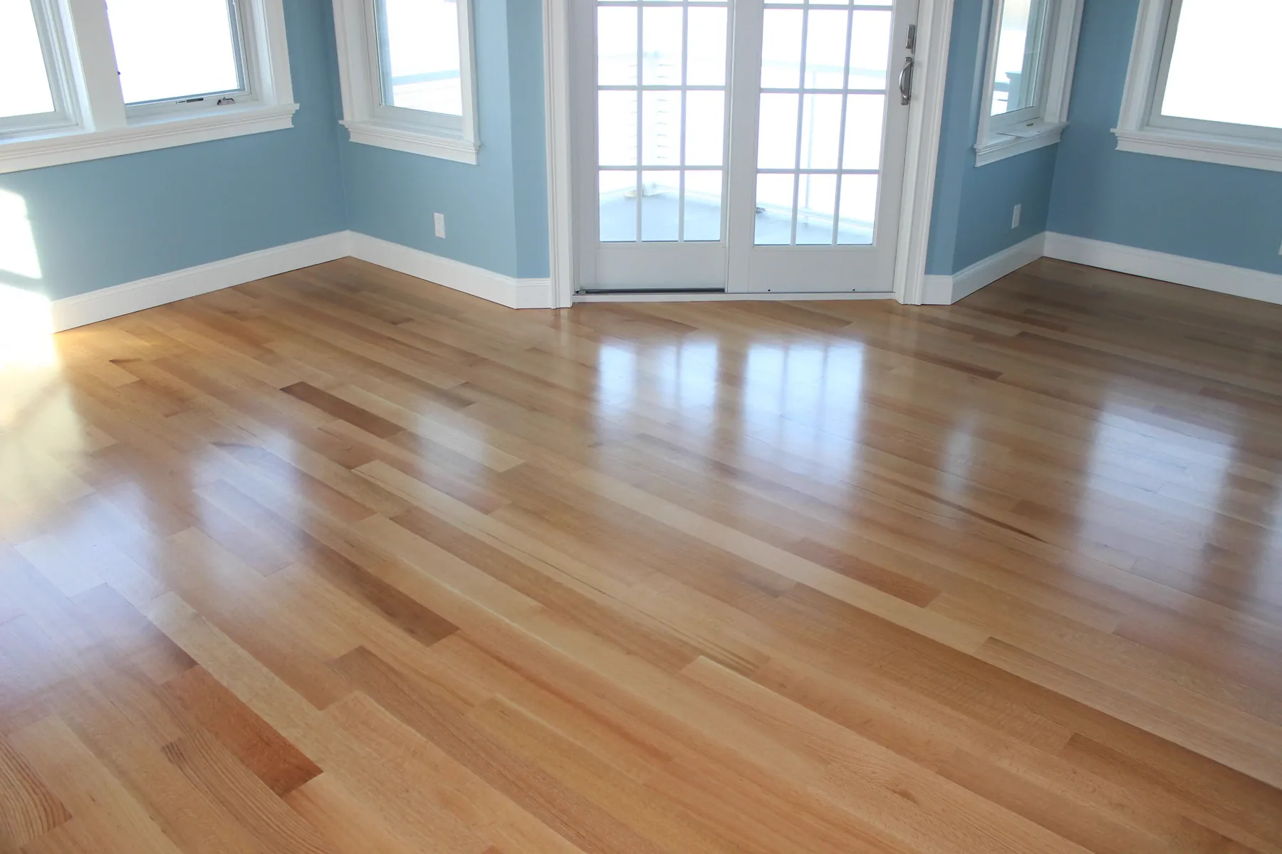 Bright room with a glossy natural hardwood floor and French doors