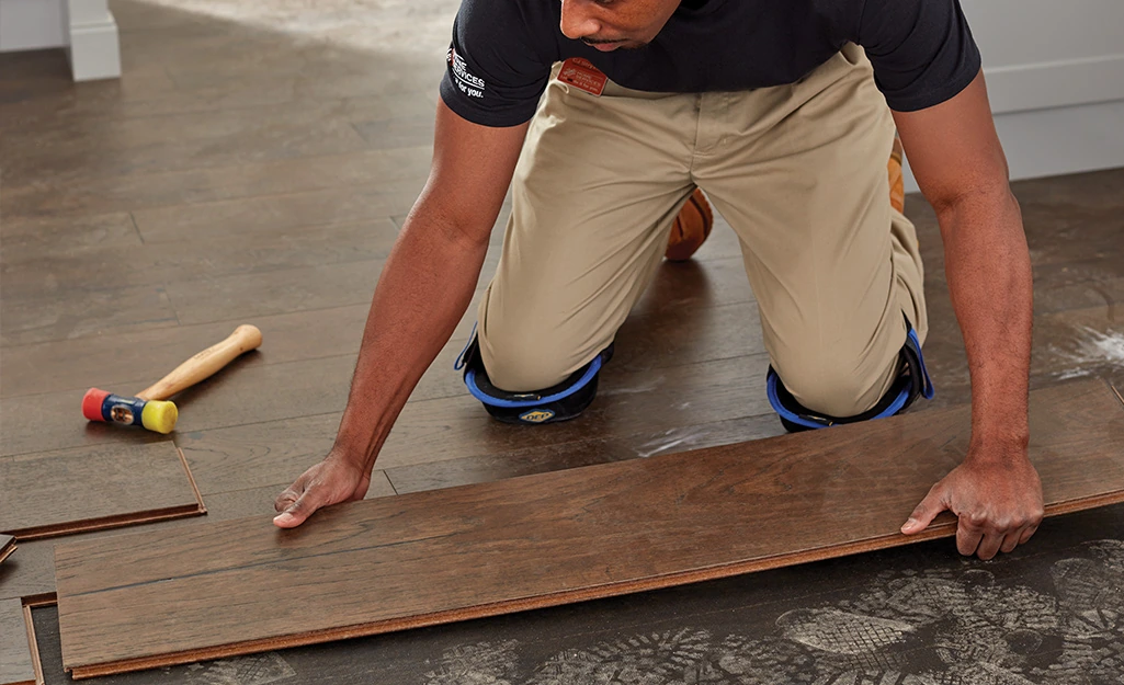 Installer laying a dark hardwood plank over underlayment