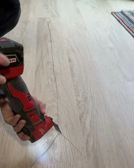 Oscillating multi-tool cutting a section out of light oak-look vinyl plank