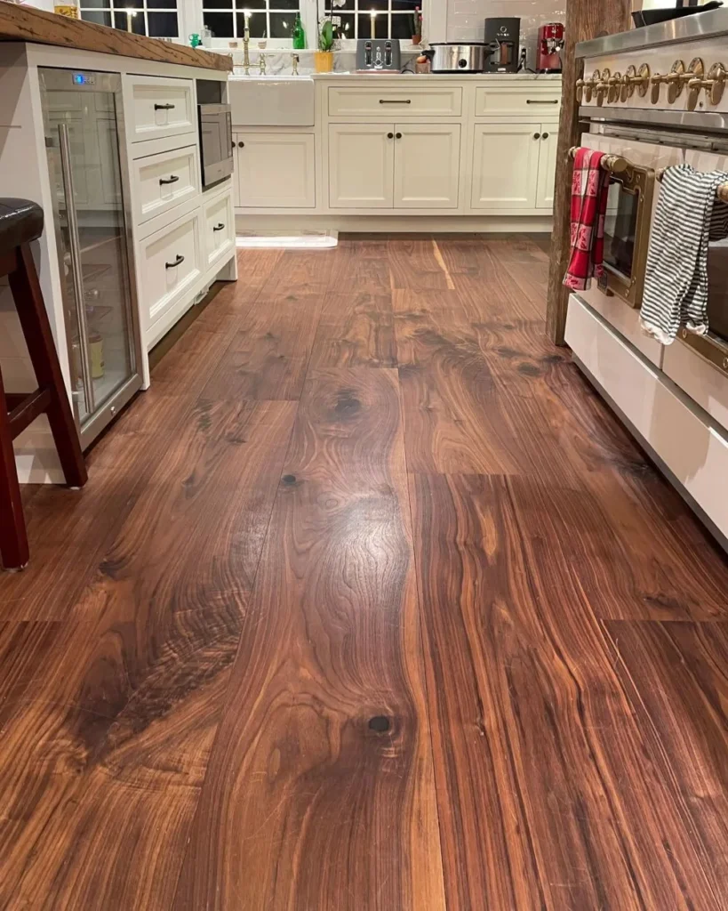 Wide-plank brown hardwood running past a kitchen island and cabinets