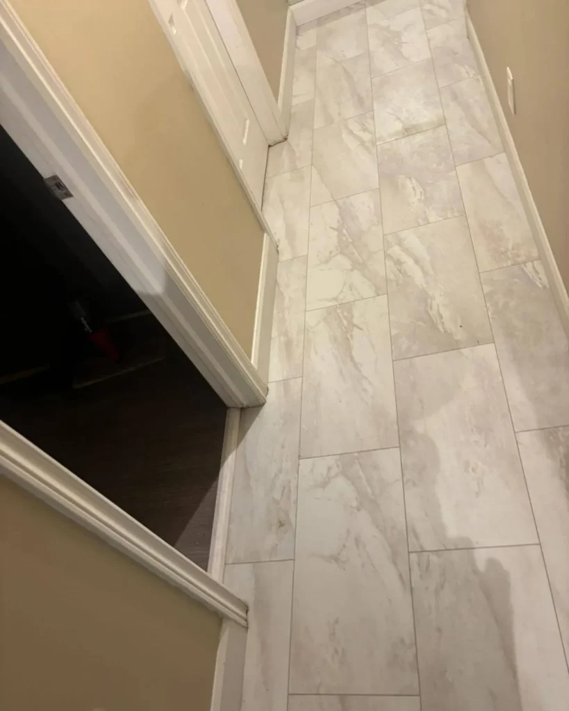 Large grey marble-look porcelain tile laid through a narrow entry hall