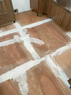 Plywood subfloor in a kitchen with the seams filled and sanded before new flooring