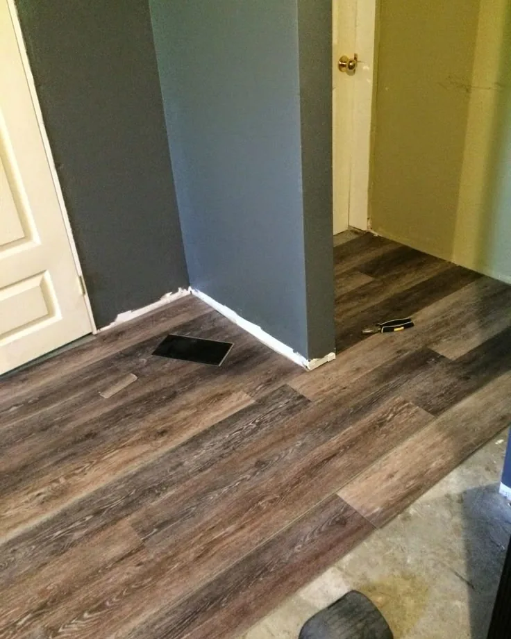 Brown wood-look vinyl plank laid in a back-door mudroom before the baseboards go on