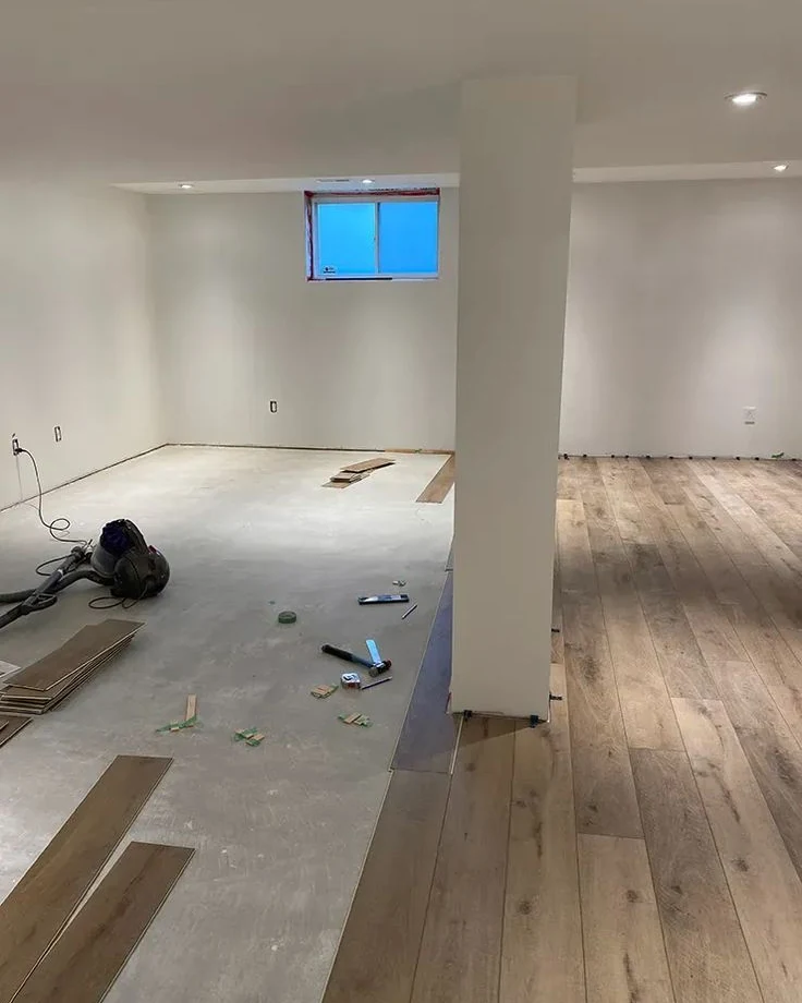 Basement slab part-covered with new oak-look vinyl plank around a support column